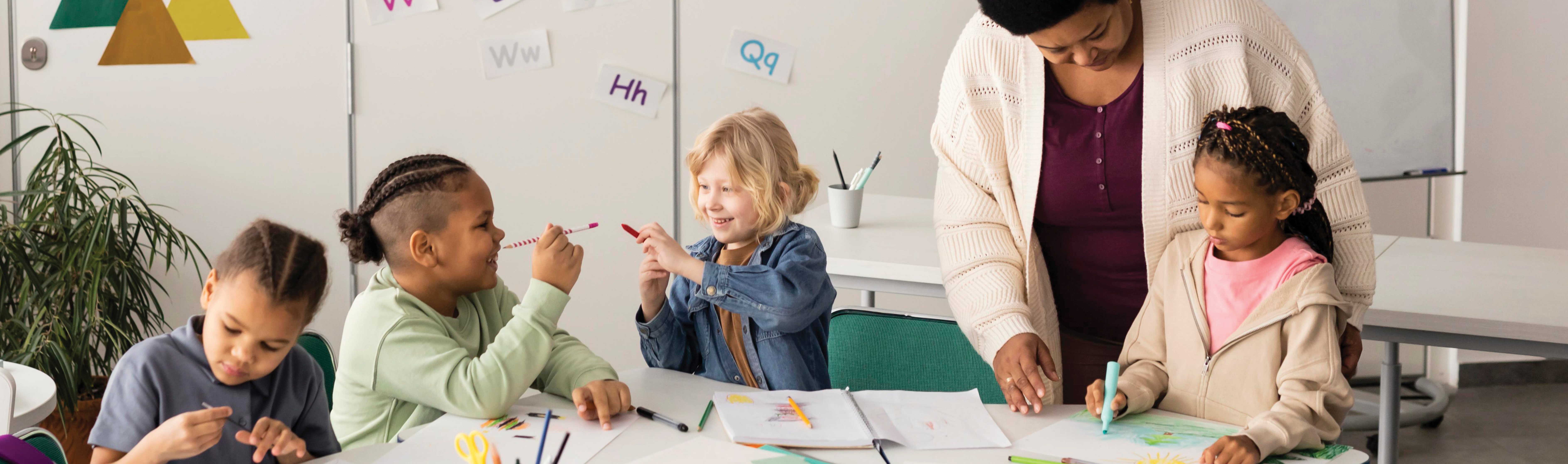 a teacher working with a group of young children who are drawing.